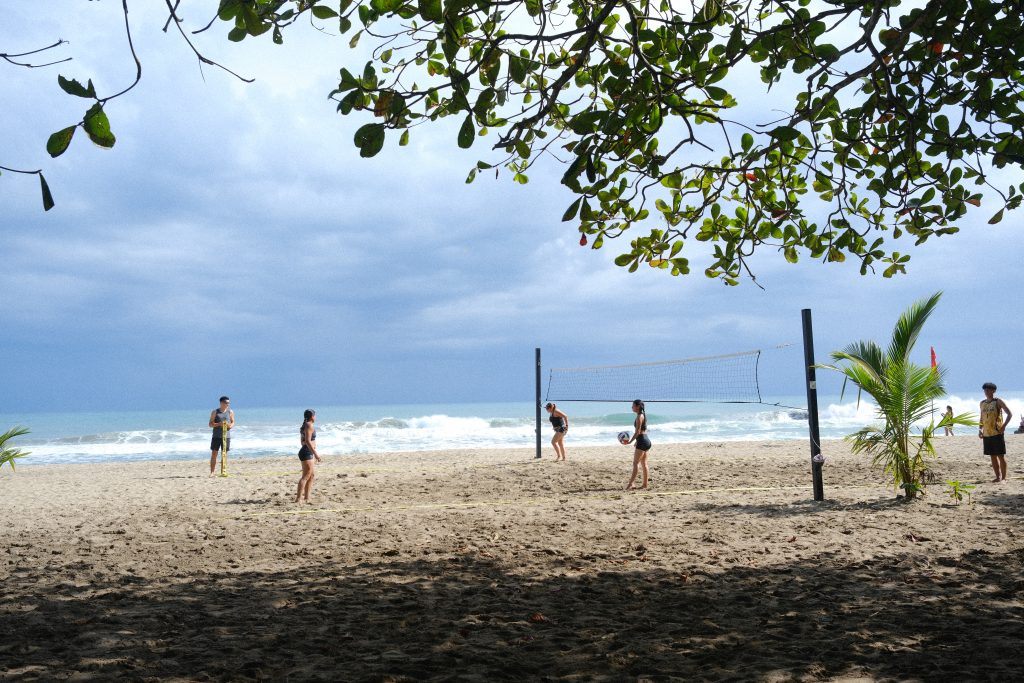 Un groupe de jeunes personnes jouant au beach-volley sur le sable devant l'océan Pacifique.