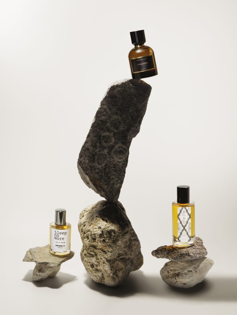 Flacons Meo Fusciuni Viole Nere et Sleep no More posés sur des pierres sombres volcaniques.